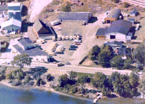 Aerial view of a group of Demers industrial buildings and surrounding grounds near a body of water
