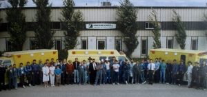 Group photo of workers standing in front of a building with Crestline ambulances parked behind them