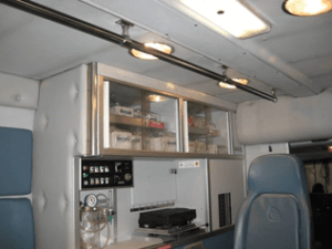 Interior of a Demers ambulance patient compartment with seating, storage cabinets, and medical equipment