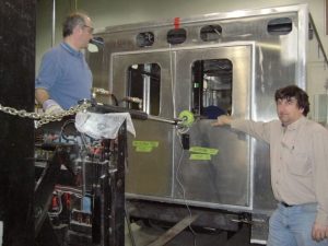 Two Demers workers standing beside an ambulance body inside a manufacturing facility