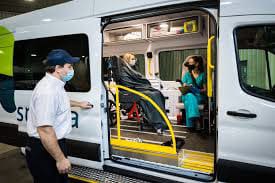 EMS personnel assisting a patient inside a Demers ambulance with the side door open