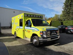 Yellow Demers ambulance parked outdoors near an industrial building