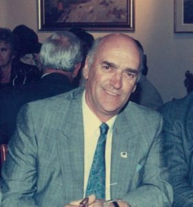 Portrait of a man wearing a suit and tie, seated indoors