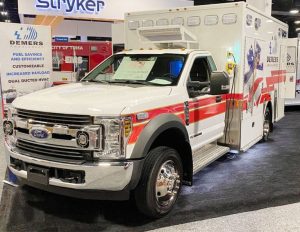 White box-style Demers ambulance displayed indoors at a trade show