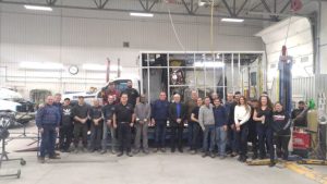 Group of Demers employees standing together in front of a half-assembled ambulance