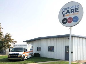 Industrial building with a “Customer Care Centre” sign and a Demers ambulance parked nearby