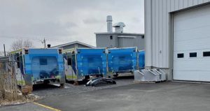 Demers ambulance bodies positioned outdoors near an industrial building