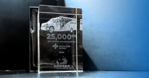 Glass award displayed on a surface with engraved text and vehicle imagery